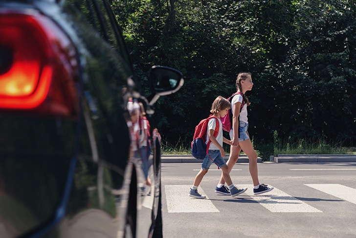Crianças atravessando a rua na faixa de segurança.