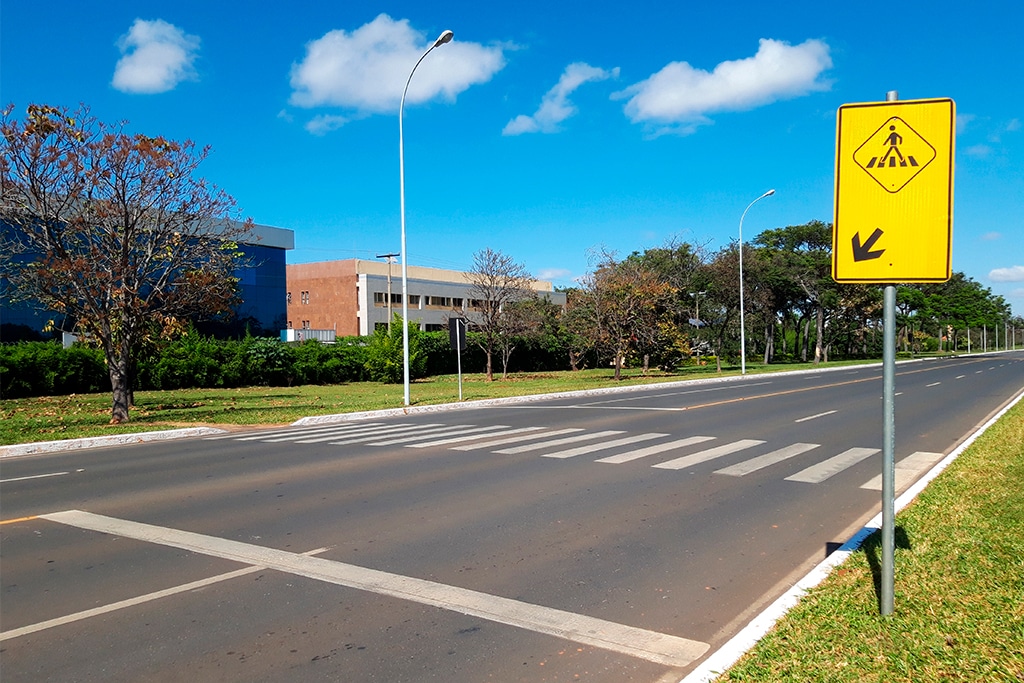 Rua com placa indicativa para passagem de pedestres